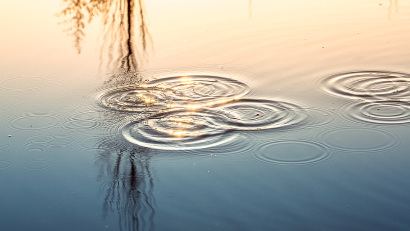 Wassertropfen fallen auf eine Wasseroberfläche.