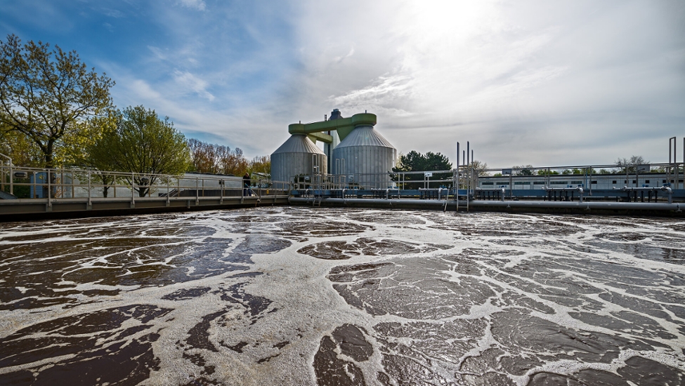 Ein Belebungsbecken auf dem Klärwerk Köln Langel. Im Hintergrund sind die beiden Faultürme .