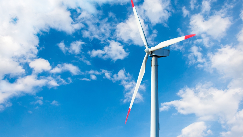 Ein Windrad vor blauem Himmel mit weißen Wolken.