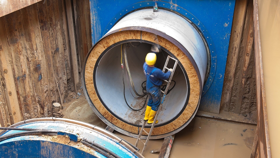 Baumaßnahme eines Rohrvortriebes. Ein Mitarbeiter steht auf einer Leiter.