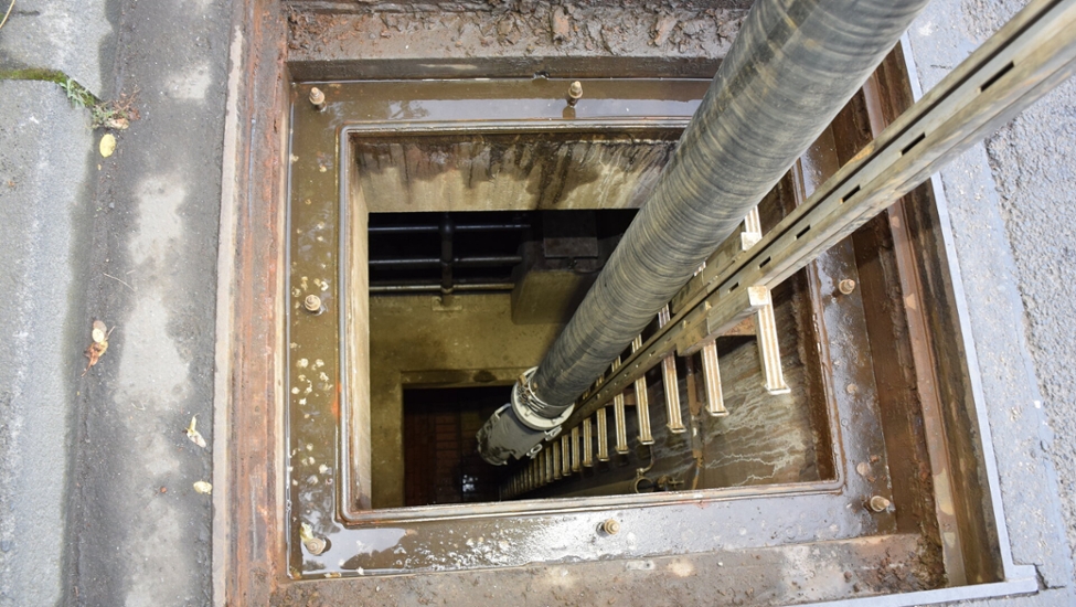 Blick auf einen Schacht zum Einstieg i das Kanalnetz. Zur Reinigung des Kanals führt ein Saugschlauch bis zur Schachtsohle.