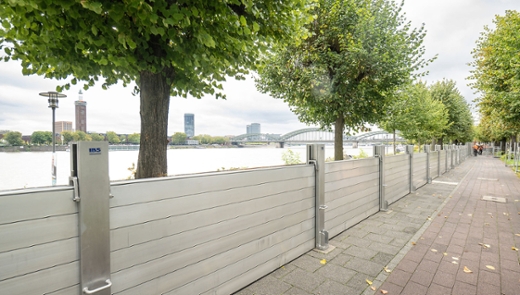 Eine aufgebaute Hochwasserschutzwand. Im Hintergrund ist der Rhein und die Hohenzollernbrücke zu sehen.