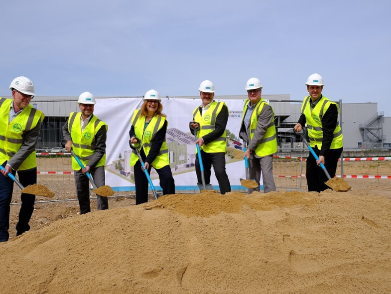 Sechs Personen in Arbeitskleidung setzen den symbolisch ersten Spatenstich zum Bau der Klärschlammverbrennungsanlage.