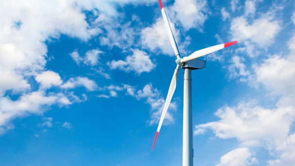 Ein Windrad vor blauem Himmel mit weißen Wolken.