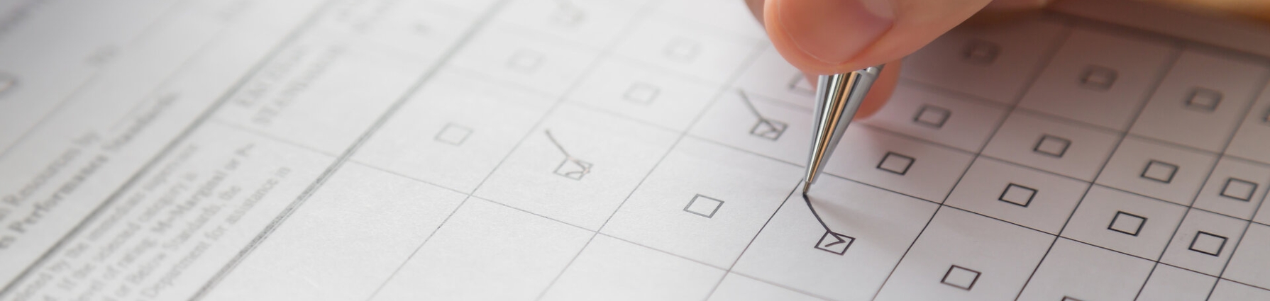 Eine Person füllt einen Fragebogen aus. Der Fragebogen besteht aus kästchen die mit einem Haken bestätigt werden müssen. Von der Person ist lediglich die Hand zu sehen.