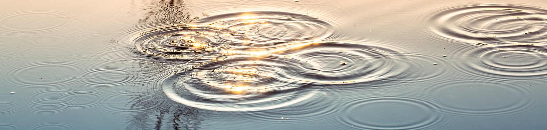Wassertropfen fallen auf eine Wasseroberfläche.